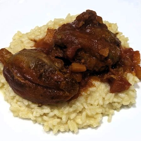 Lamb with Red Sauce sitting on a bed of risotto rice