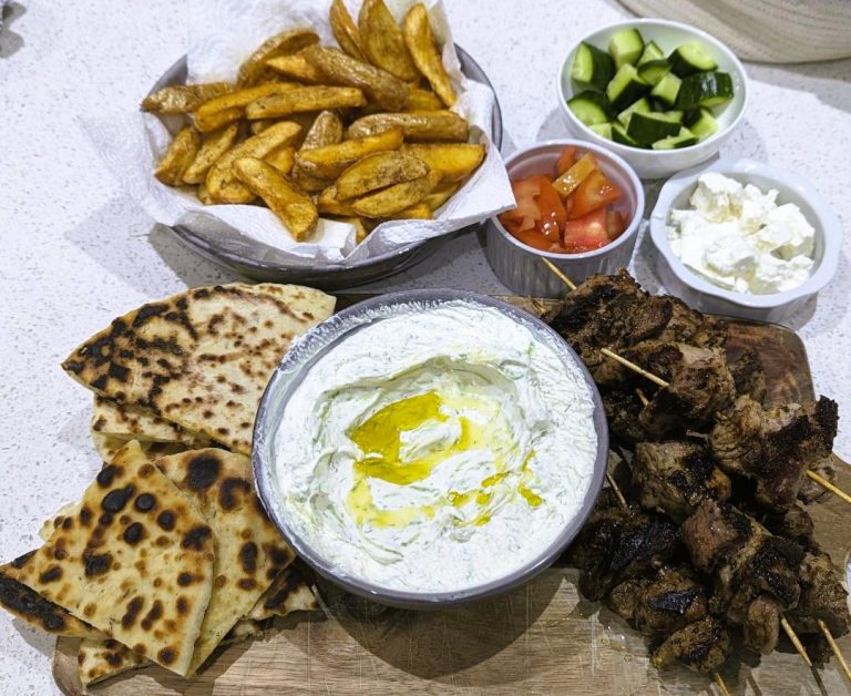 Tzatziki dip along with pita bread, meat, hot chips and salad