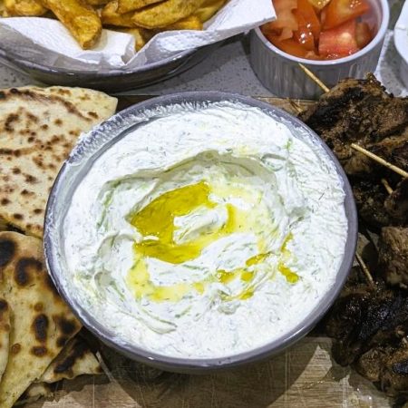 Tzatziki dip along with pita bread, meat, hot chips and salad