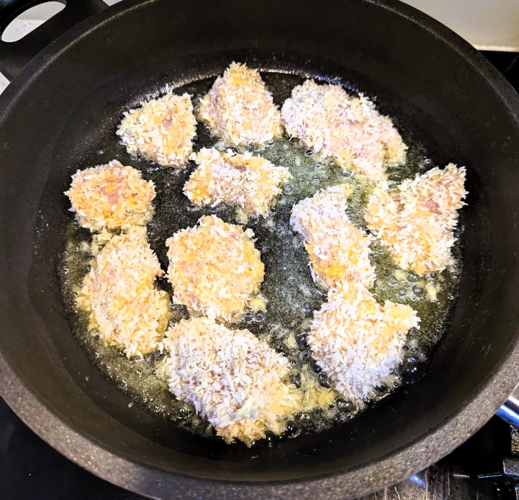 Raw chicken nuggets in a fry pan